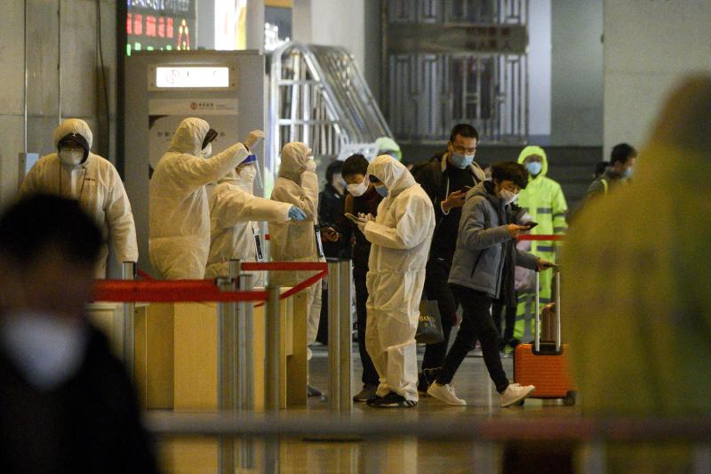 oruyucu kıyafetler giyen sağlık çalışanları 9 Şubat 2020'de Şanghay'daki Şangay Güney tren istasyonunda yolcuların seyahat geçmişini kontrol ediyor AFP.jpg