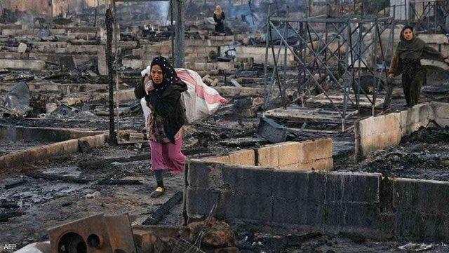 Yangından viraneye dönmüş mülteci kampını terkeden Suriyeli sığınmacı bir kadın-fotoğraf-AFP.jpg