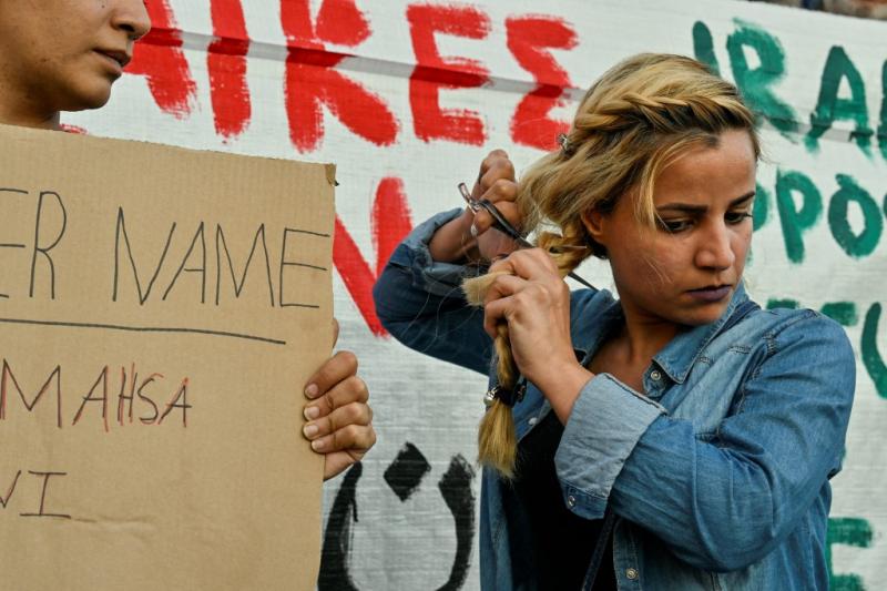 Brüksel- İran Büyükelçiliği önünde protesto için saçını kesen İranlı bir kadın.Görsel-AFP .jpg
