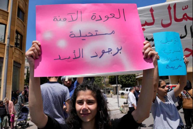 Bir protestocu, 1 Mayıs'ta Beyrut'ta düzenlenen İşçi Bayramı yürüyüşünde Arapça 'Esad varken güvenli bir dönüş imkansızdır' yazan bir pankart taşıyor. Fotoğraf_ Hüseyin Malla_AP.jpg