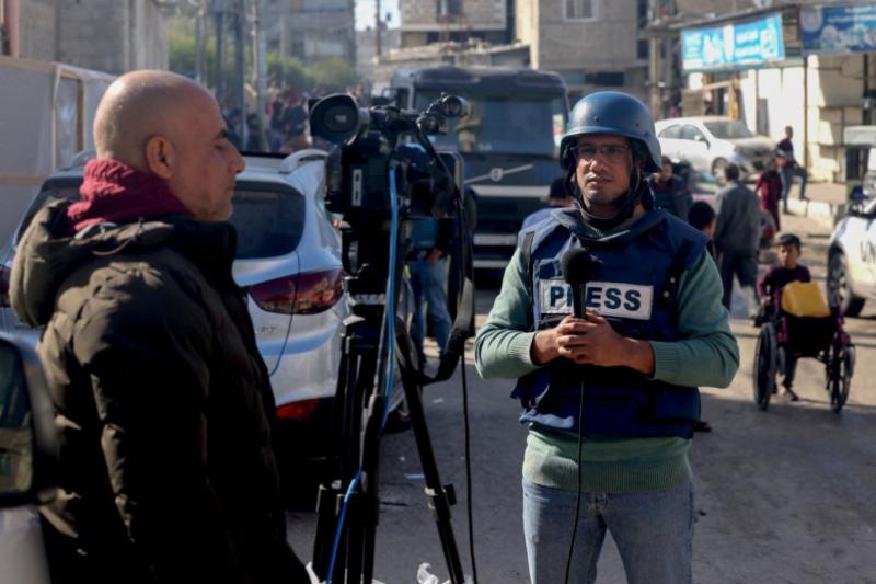 Gazze'nin güneyindeki Refah şehrinin caddesinde bir gazeteci, haber için kamera önünde. Fotoğraf-AFP.jpg