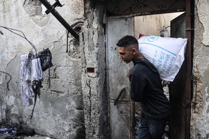  Gazze'de bir evin bombalanmasının ardından Filistinli bir genç, bir miktar un taşıyor.jpg