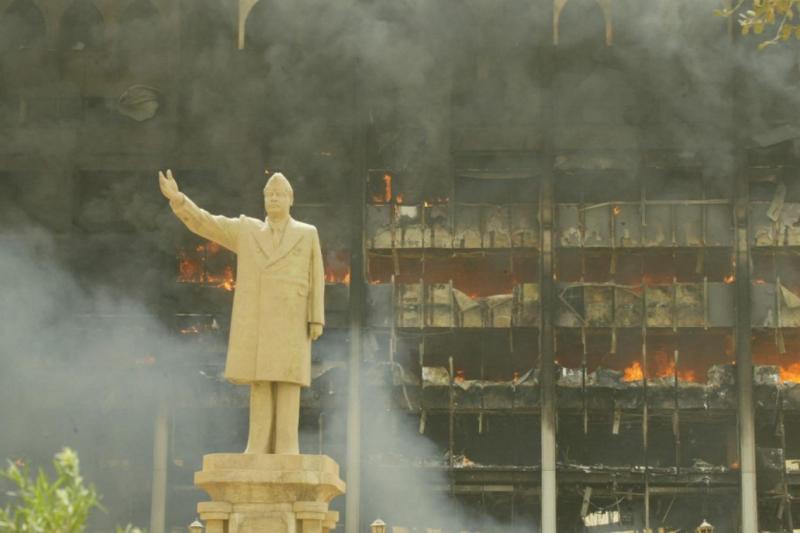 İşgalde yangın yerine dönen Bağdat'ta savaş tankları ve ayakta duran Saddam heykeli Fotoğraf-AFP.jpg