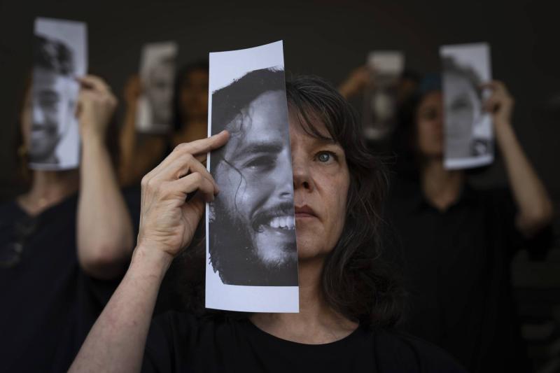 Gazze Şeridi'nde esir tutulan İsraillilerin yakınları, Tel Aviv'de düzenlenen bir gösteri sırasında yakınlarının fotoğraflarını tutuyor AP.jpeg