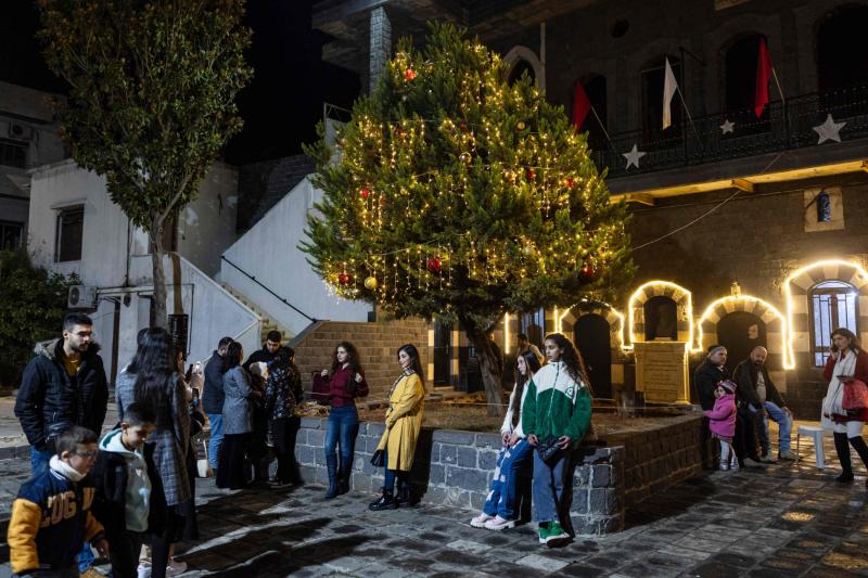 Humus'taki Azize Meryem Ana Kilisesi'nde Noel ağacının önünde poz veren Suriyeli Hristiyanlar, 20 Aralık 2024 / Fotoğraf: AFP