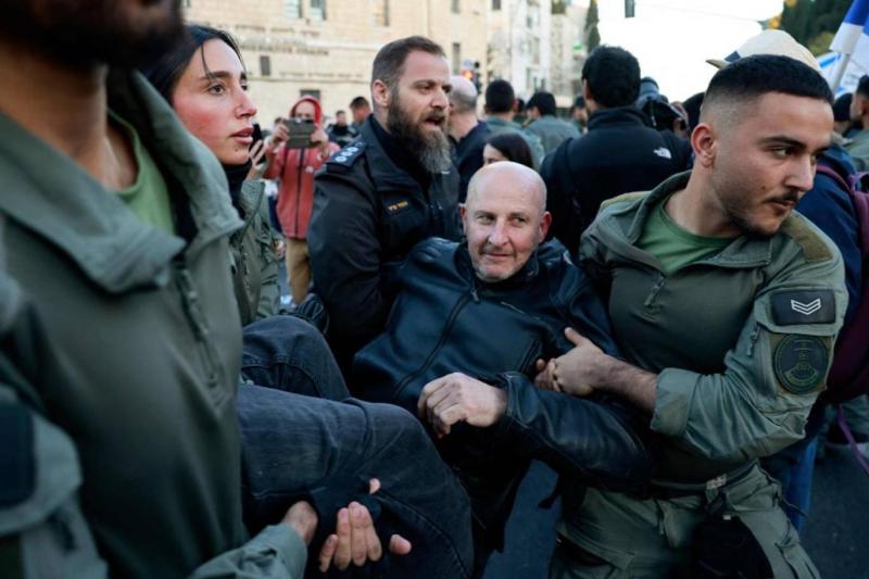 Netanyahu politikasını protesto eden bir muhalif yaka paça alınıp götürülüyor / Fotoğraf: AFP