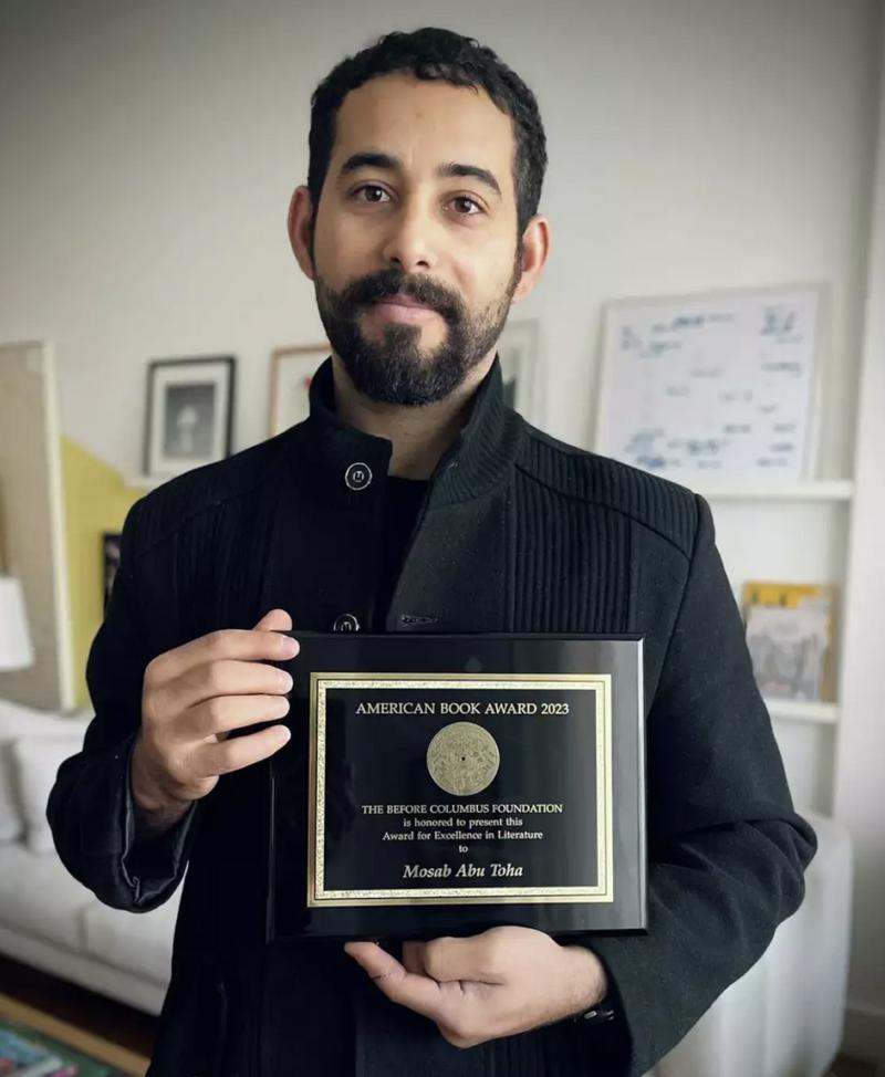 Musab Ebu Tuha, edebi çalışmaları onuruna verilen American Book Ödülü'nü elinde tutarken