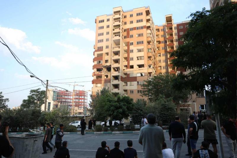 İsrail saldırısıyla Tahran'da hasar gören binalardan birinin önündeki İranlılar / Fotoğraf: AFP