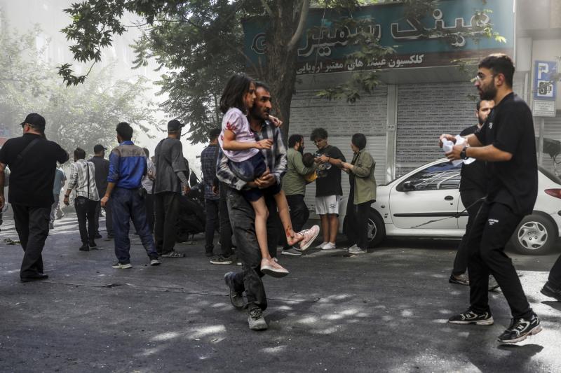 İsrail'in İran'a yönelik saldırıları sırasında Tahran'ın merkezinde meydana gelen patlamada yaralanan bir kızı taşıyan bir adam, 15 Haziran 2025 / Fotoğraf: AP