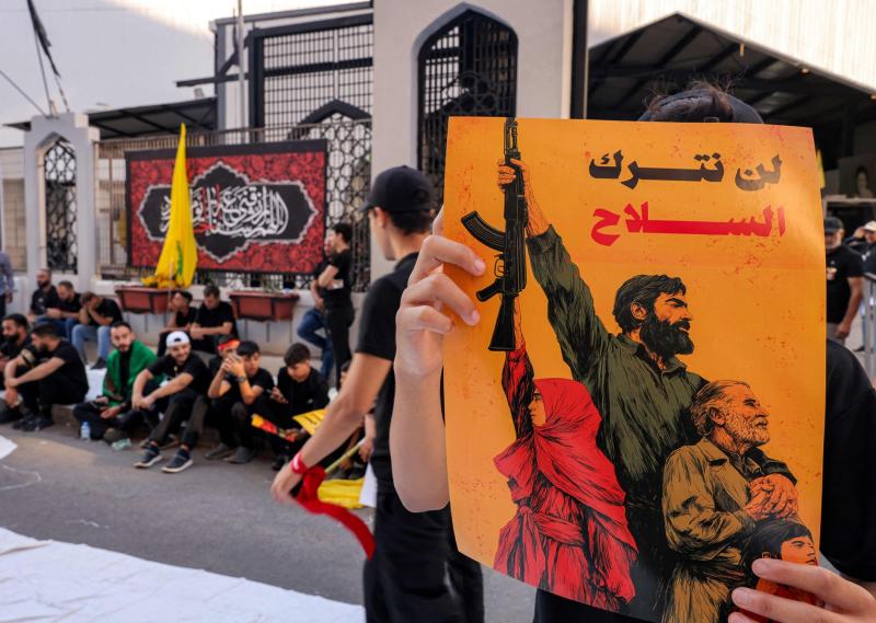 Beyrut’un güney banliyösünde Hizbullah'ın Aşure Günü törenleri sırasında ‘Silahları bırakmayacağız’ yazılı bir pankart taşıyan bir kişi, 6 Temmuz 2025 / Fotoğraf: AFP