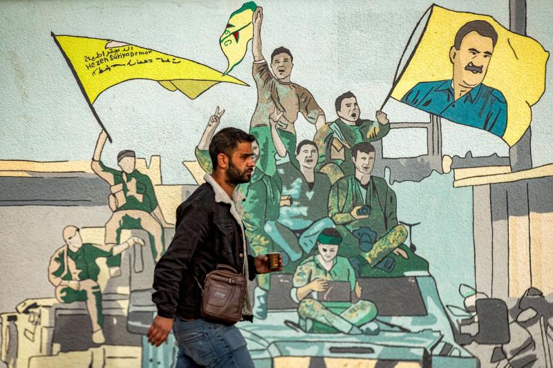 Kamışlı’da SDG destekçilerinin Abdullah Öcalan'ın resmini kaldırdığı duvarın önünden geçen bir adam, 16 Aralık 2024 / Fotoğraf: AFP