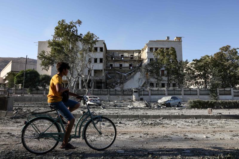 İsrail bombardımanına maruz kaldıktan sonra Şam'ın merkezindeki Suriye Savunma Bakanlığı binasının önünde bisikletli bir Suriyeli, 17 Temmuz / Fotoğraf: AFP