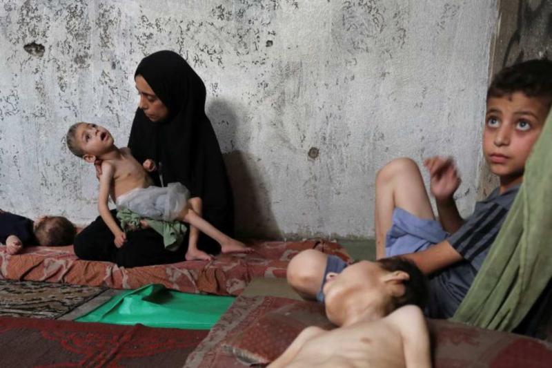 Yerinden edilmiş Filistinli anne Samah Matar, beyin felci ve yetersiz beslenme sorunu yaşayan oğlu Ameer’i kucağında tutarken, aynı durumdaki diğer oğlu Yusuf, Gazze Şehri’ndeki bir okulda, bir şilte üzerinde yatıyor / Fotoğraf: Mahmoud Issa-Reuter