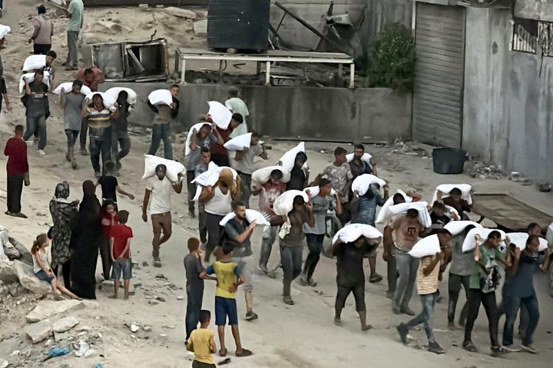 Gazze Şeridi'nin güneyindeki Han Yunus'ta gıda malzemesi taşıyan bir kamyona baskın düzenlendikten sonra un çuvallarını taşıyan adamlar, 22 Temmuz 2025 / Fotoğraf: AFP