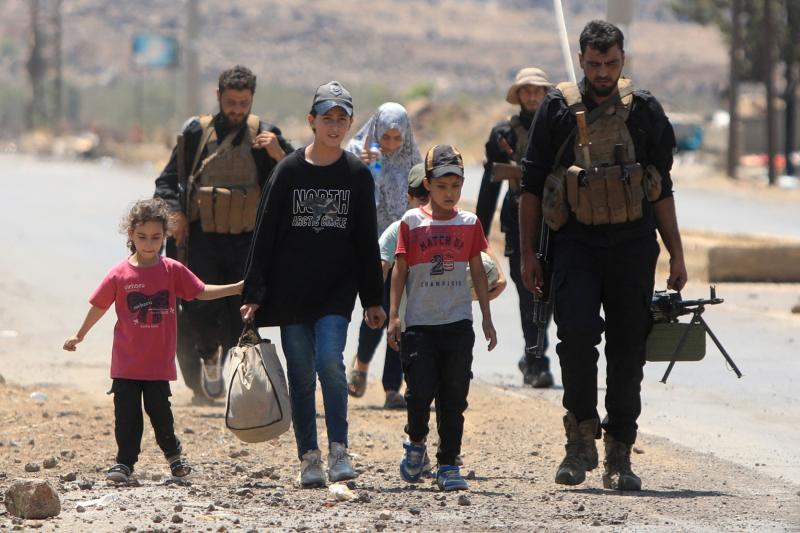 Suveyda'dan ayrılan bir aileye eşlik eden Suriye güvenlik güçlerinin bir üyesi, 21 Temmuz 2025 / Fotoğraf: AFP