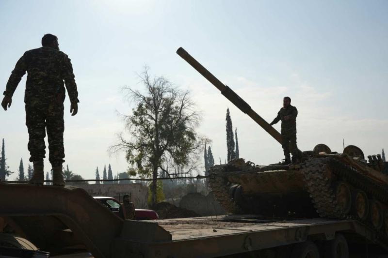 İki muhalif militan Halep'te ele geçirilen Suriye tanklarının üstünde poz veriyorlar, 20 Kasım 2024