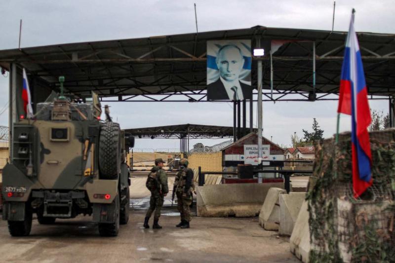 Rus askeri araçların Suriye’nin batısındaki Lazkiye ilinde Rusya tarafından kiralanan Hmeymim Hava Üssü’ne girişi sırasında yukarıda asılı duran Rusya Devlet Başkanı Vladimir Putin’in bir fotoğrafı, 29 Aralık 2024 / Fotoğraf: AFP