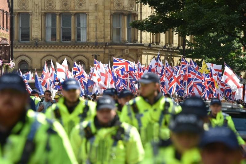 Manchester'da düzenlenen ve toplu sınır dışı çağrısı yapan göçmen karşıtı bir protesto gösterisi sırasında aşırı sağcı grup Britain First (Önce Birleşik Krallık/BNP) grubu destekçilerinin ulusal bayraklarla katıldığı yürüyüşte görevli polis memurları, 2 