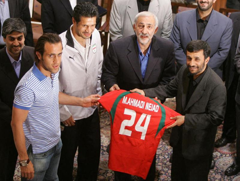 İran'ın eski Cumhurbaşkanı Mahmud Ahmedinejad, İran milli takımının ünlü oyuncusu Ali Dayi'den, takımın Dünya Kupası'na katılmak üzere Almanya'ya gitmeden önce milli takım forması hediyesini alırken, 3 Haziran 2006 / Fotoğraf: AFP