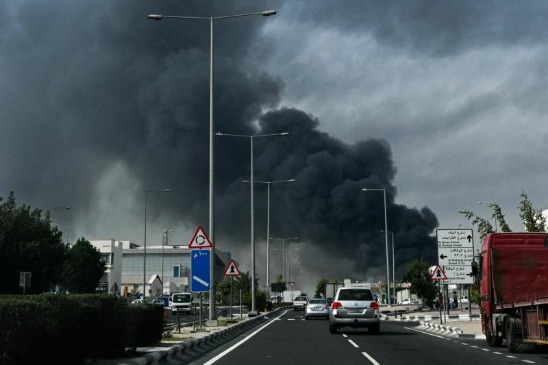 Katar’ın başkenti Doha'daki sanayi bölgesinde İran'ın düzenlediği iddia edilen bir hava saldırısı sonucu yükselen dumanların önünden geçen araçlar, 1 Mart 2026 / Fotoğraf: AFP