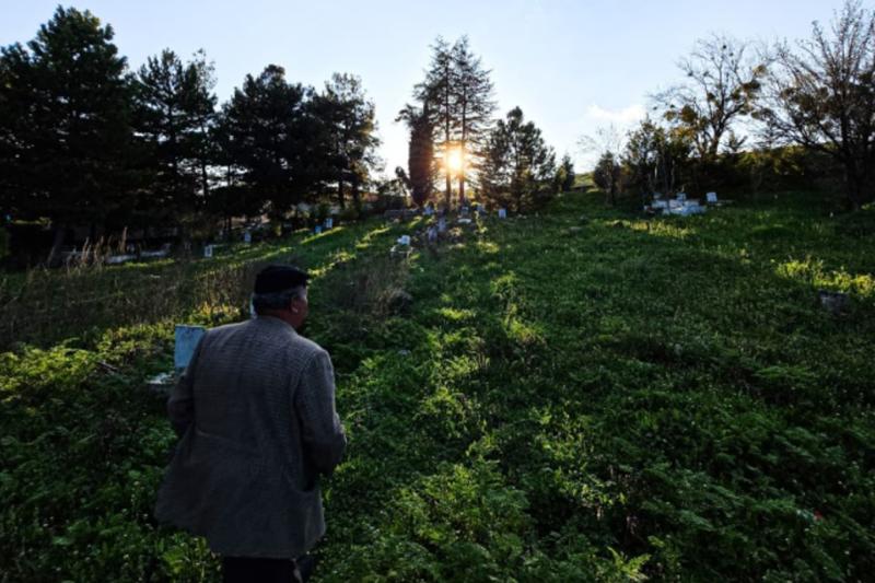 Kemal Öner ile köy mezarlığında, çamların arasından süzülen güneş ışığının izinde