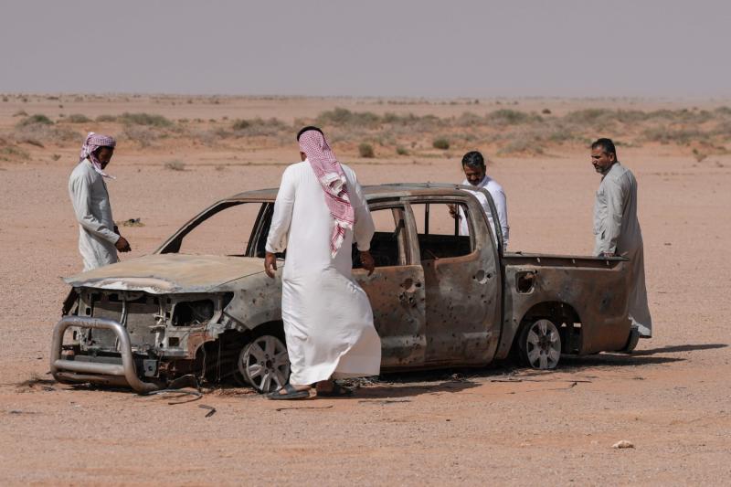 Irak'ın güneybatısındaki Necef çölünde, enkaz halindeki bir kamyonetin etrafında toplanan adamlar. İsrail güçleri, İran'a karşı savaş sırasında Irak çölünde eski bir havaalanını kullanarak geçici bir üs kurmuştu,12 Mayıs 2026 / Fotoğraf: AFP