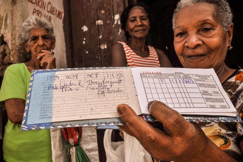 Santiago de Cuba’da yaşayan bir kadın, devlet sübvansiyonları sayesinde düşük fiyatlarla gıda temin etmesini sağlayan rasyon kartı “libreta”yı gösteriyor / Fotoğraf: AFP