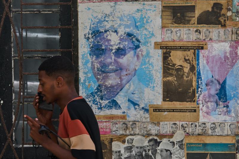 Havana'da Küba Devrimi hakkında bir sergide, duvardaki Raúl ve Fidel Castro fotoğraflarının yanında bir adam telefonla konuşuyor, 20 Mayıs 2026 / Fotoğraf: AP