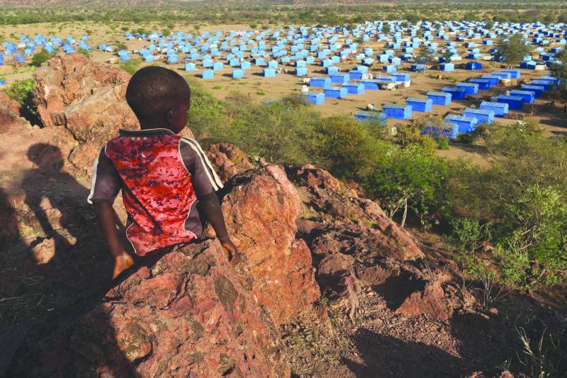 Sudan’ın Çad sınırına yakın bir mülteci kampına bakan tepenin zirvesinde oturan bir çocuk, Kasım 2023 / Fotoğraf: Reuters