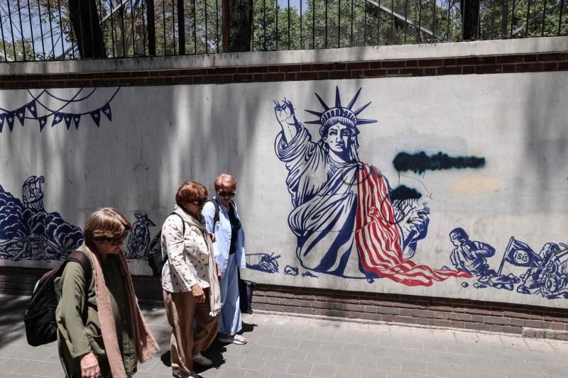Tahran’daki eski ABD Büyükelçiliği yakınlarında ABD karşıtı duvar resimlerinin önünden geçen İranlı kadınlar, 15 Haziran 2026 / Fotoğraf: AFP