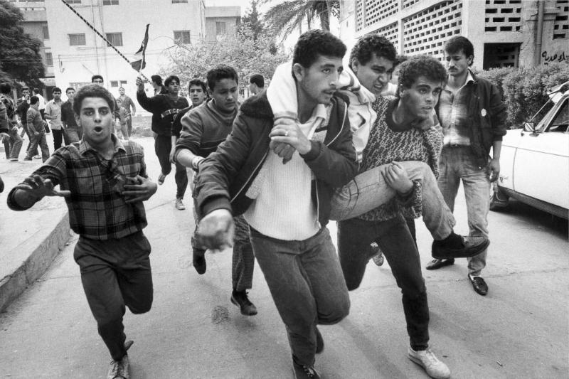  Birinci İntifada sırasında, İsrail güvenlik güçleriyle yaşanan çatışmalarda yaralanan Filistinli bir genci arkadaşları kucaklarında güvenli bir alana taşırken (1988)