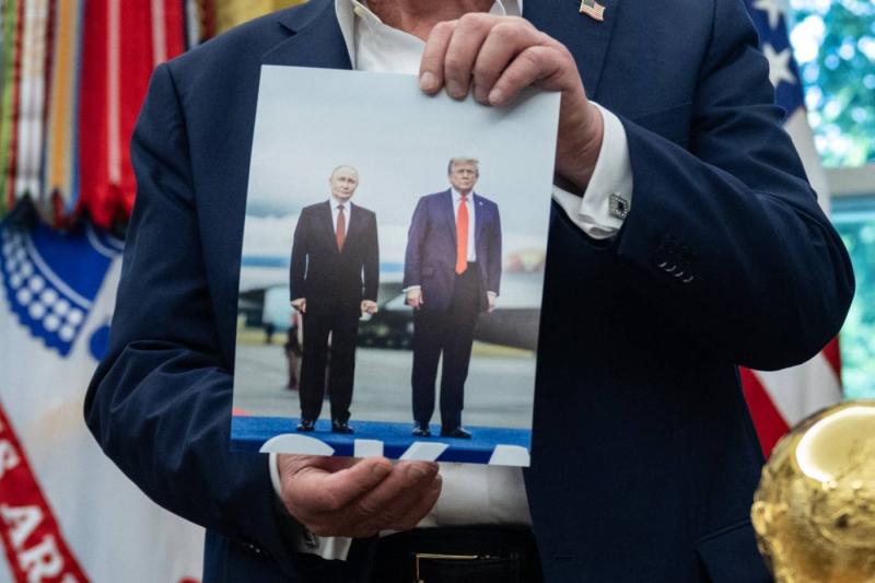 Trump, Alaska'da Putin'i karşılarken çekilmiş bir fotoğrafını gösterirken / Fotoğraf: AFP