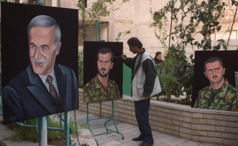 Suriyeli sanatçı Hüsam Zambarji, 13 Aralık 1999 tarihinde Şam'da, merhum Suriye Cumhurbaşkanı Hafız Esed'in (solda) oğlu Basil Esad'ı (ortada) tasvir eden tablosuna son rötuşlarını yapıyor / Fotoğraf: AFP