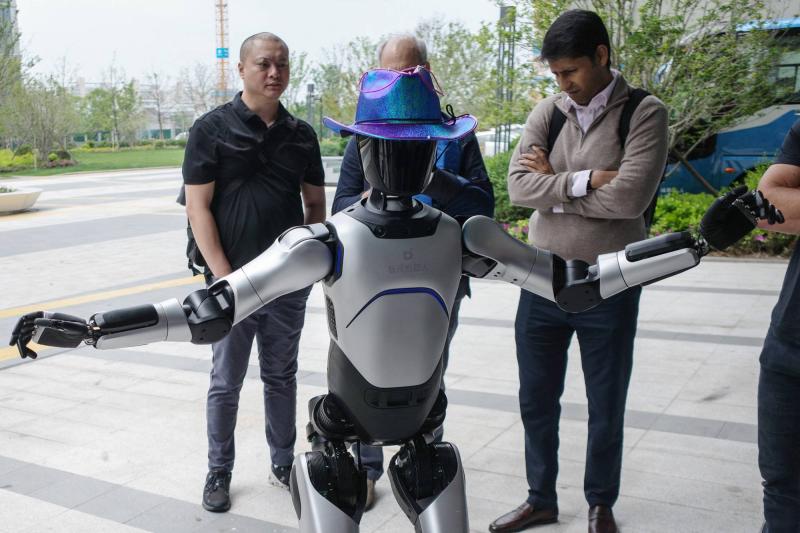 Şangay'daki AgiBot genel merkezinde insansı bir robotla etkileşim kuran ziyaretçiler / Fotoğraf: Reuters