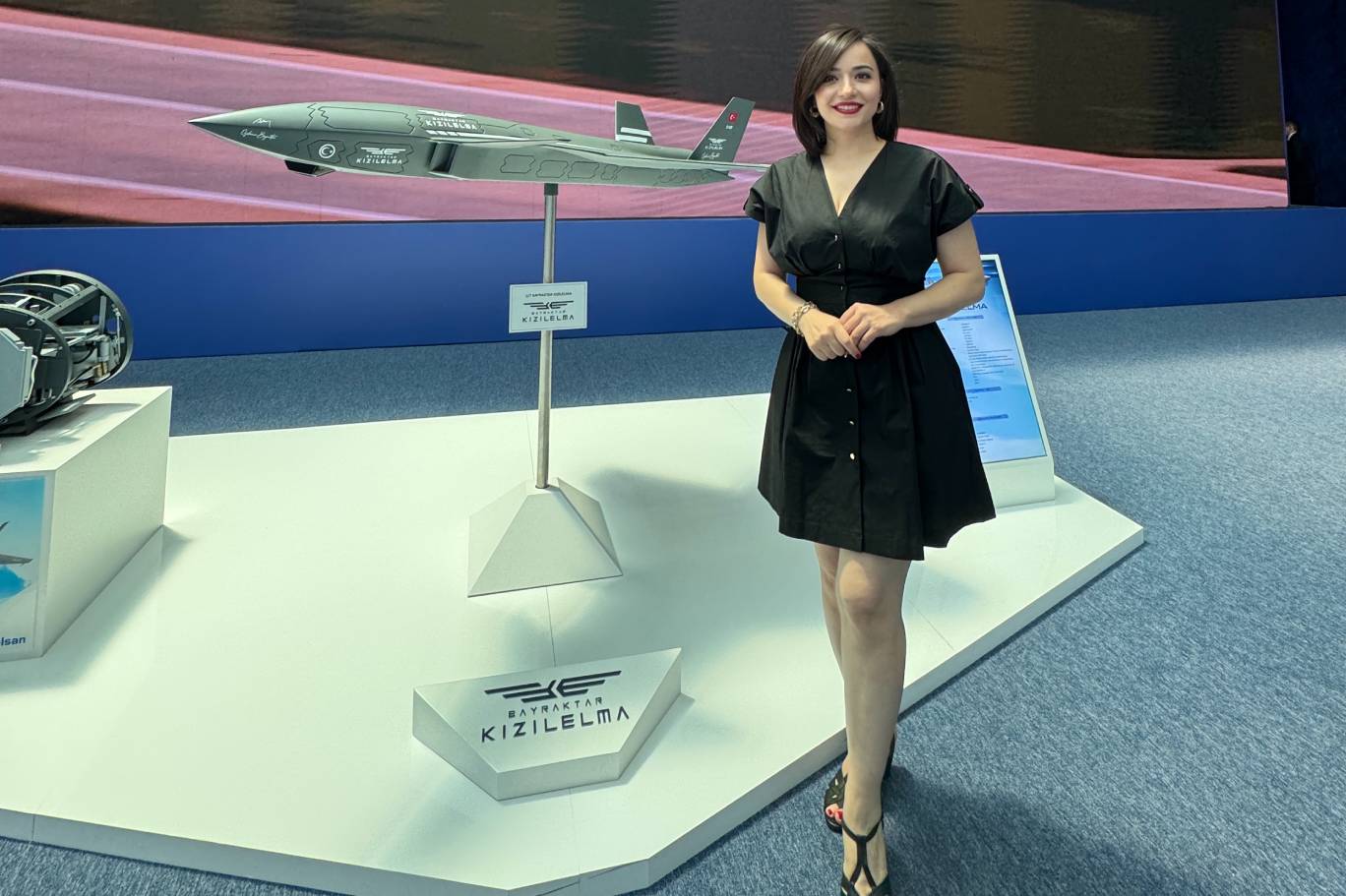 Esra Öz, NATO Savunma Sanayii Forumu'nda sergilenen Bayraktar KIZILELMA maketi önünde
